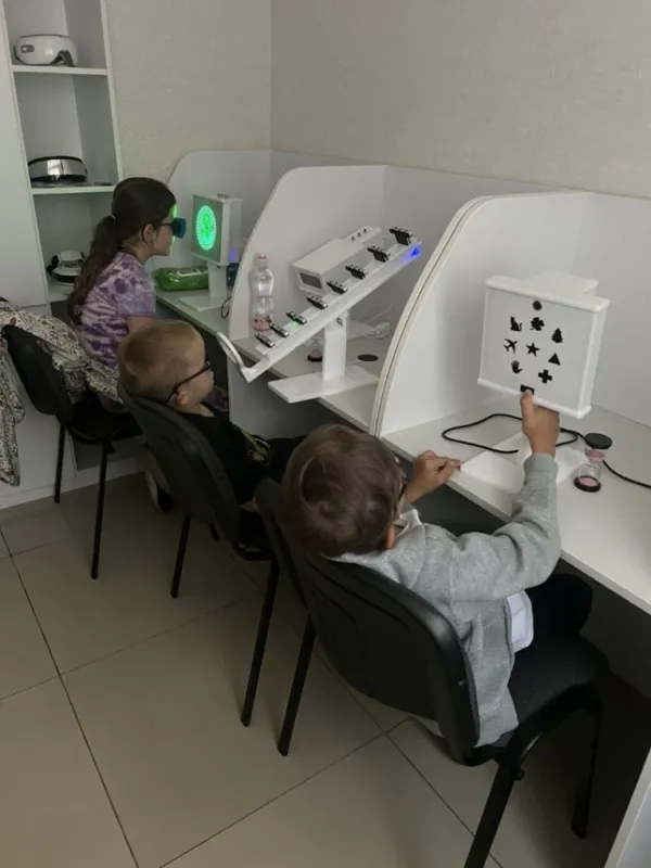 Діти в окулярах за апаратами для зору в кабінеті Оптики Фортуна в Нетішині